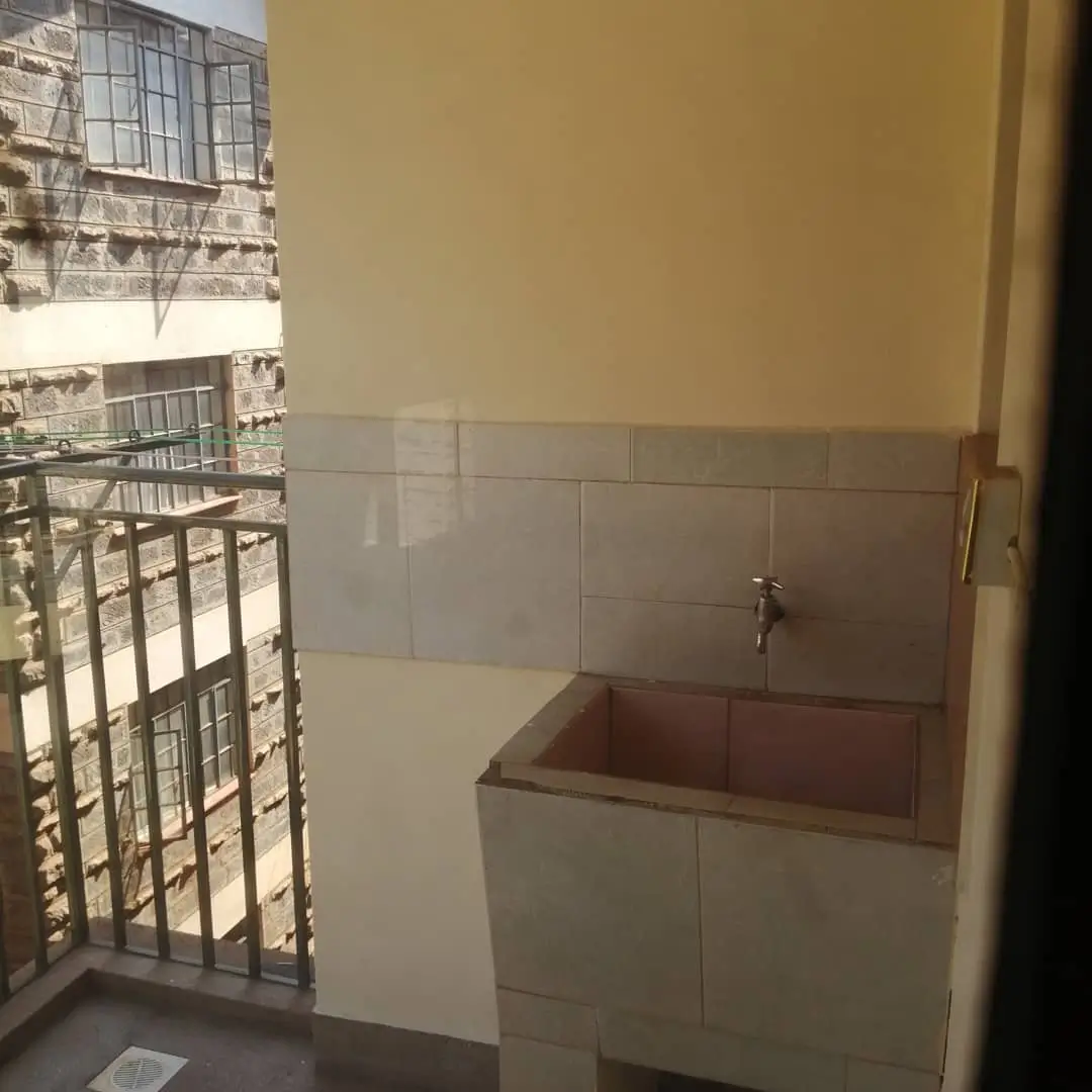 Compact laundry utility room with sink and tiled walls