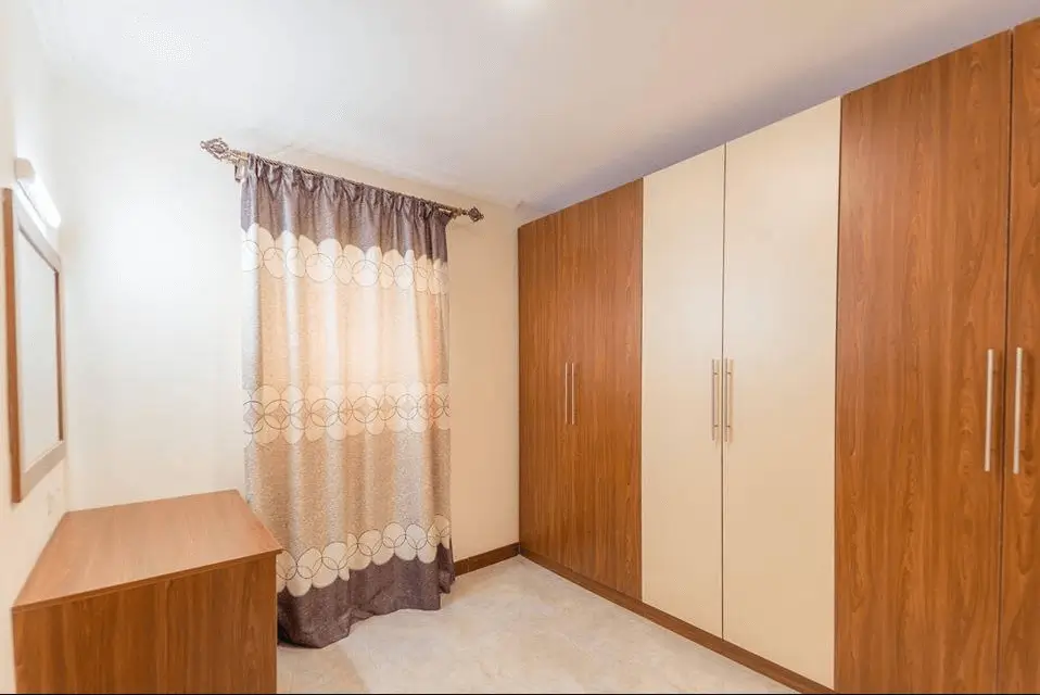Master bedroom with wooden wardrobe and sheer curtains