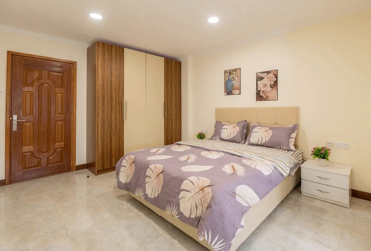 Master bedroom with patterned bedding, wooden wardrobe, yellow walls