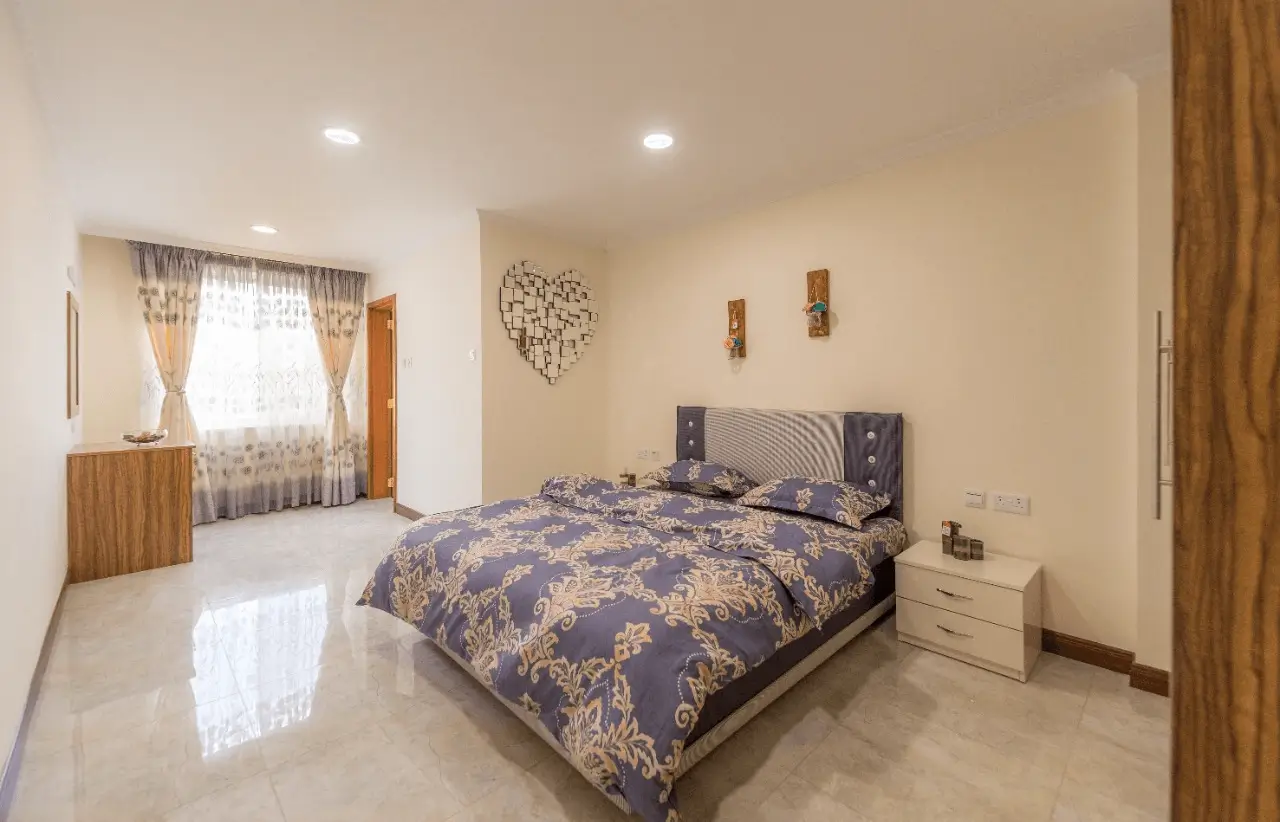 Spacious master bedroom with ornate bedding and window seating