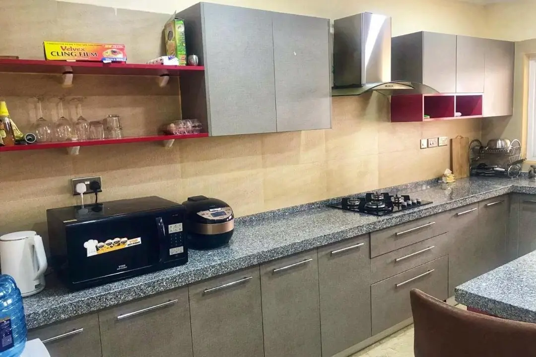 Modern kitchen with granite countertops, gas stove, and red shelving