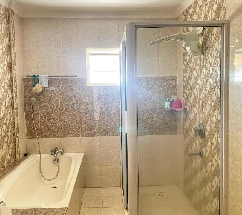 Bathroom with bathtub, shower enclosure, and patterned tile walls