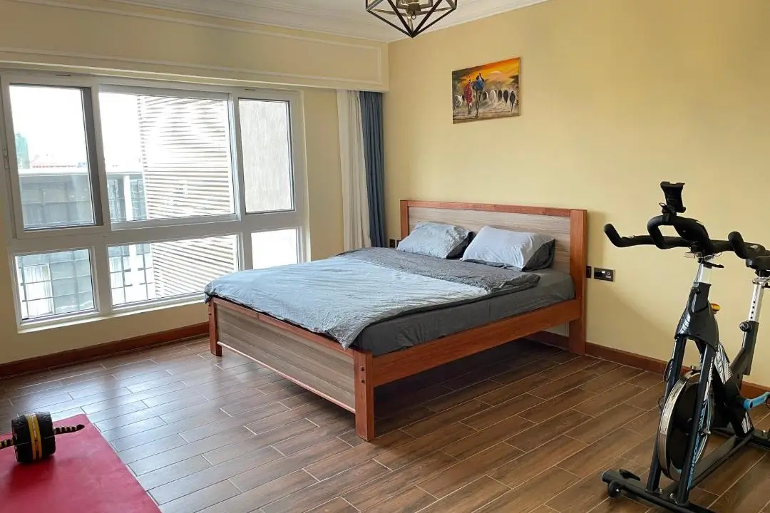 Master bedroom with wooden bed frame and large windows