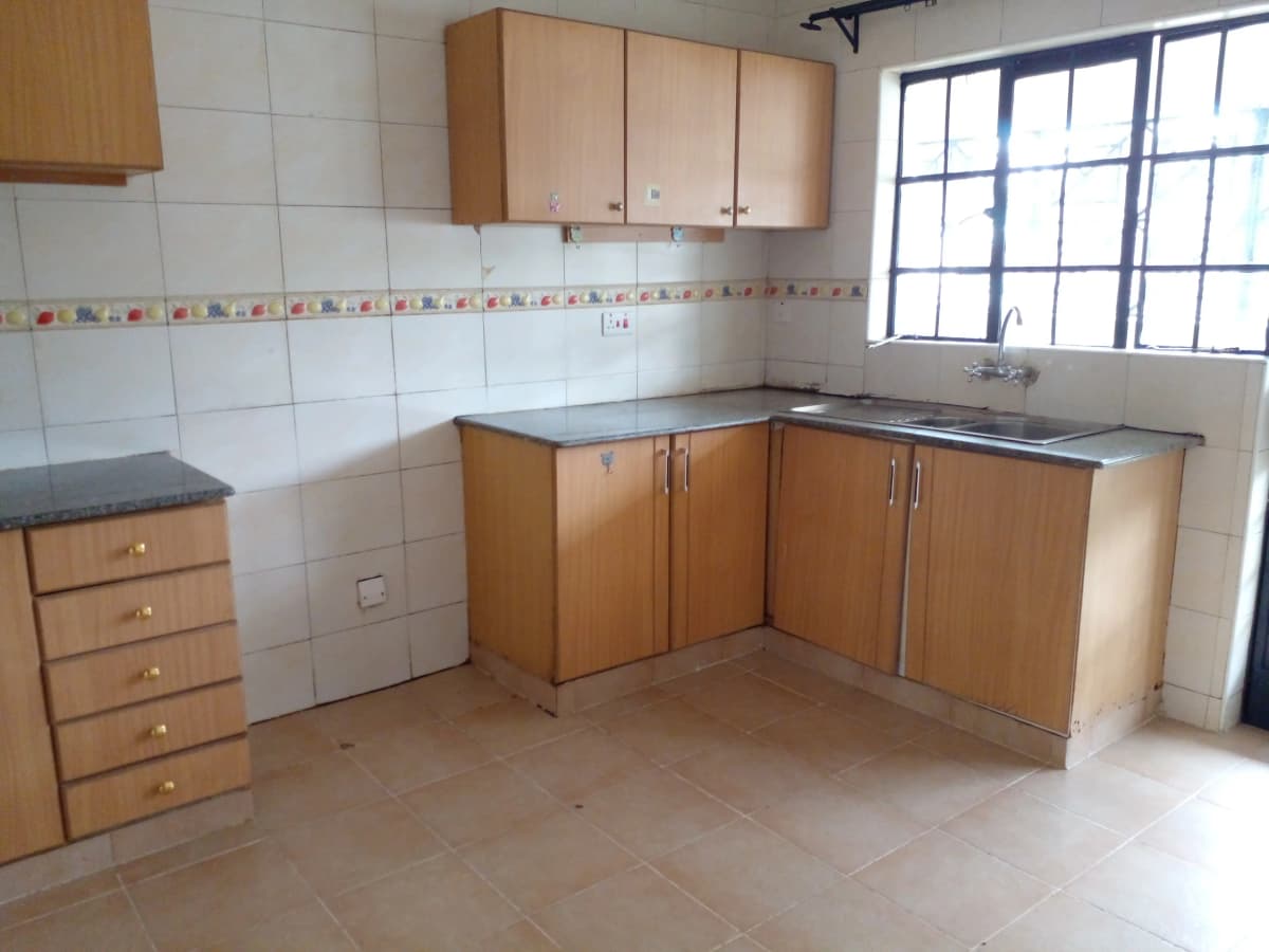L-shaped kitchen with wooden cabinets and white tiled walls