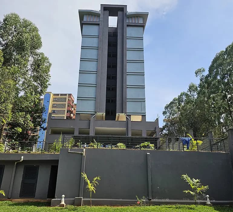 Modern dark gray high-rise building facade with landscaped compound
