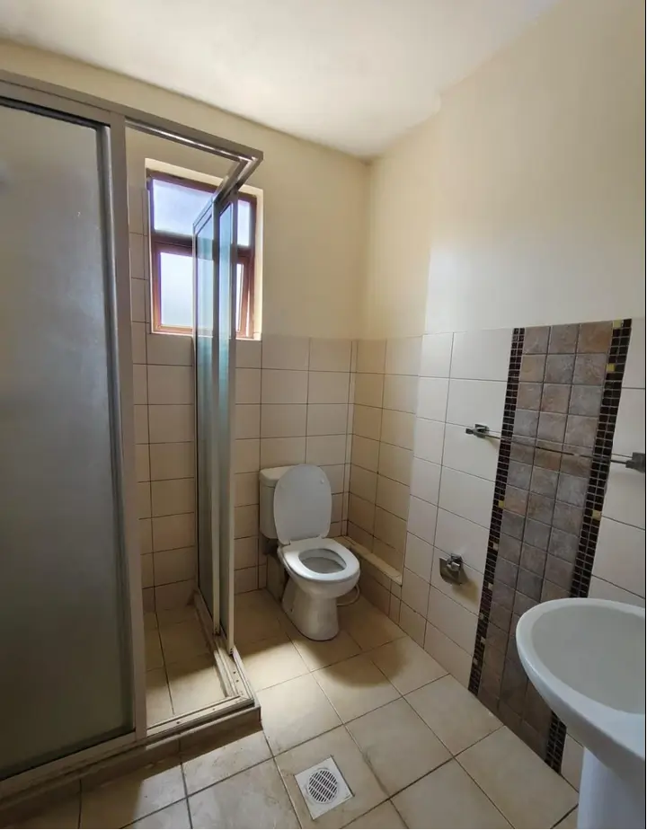 Tiled bathroom with toilet, sink, and shower enclosure