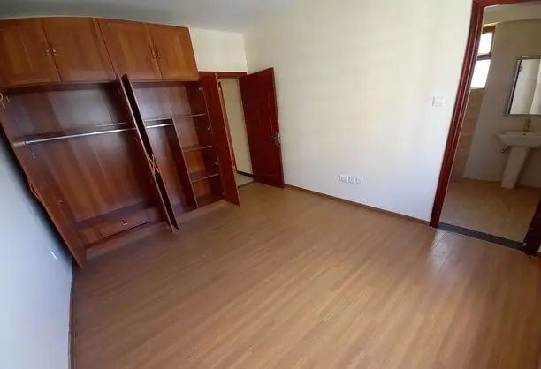 Spacious bedroom with wooden flooring and built-in wardrobes