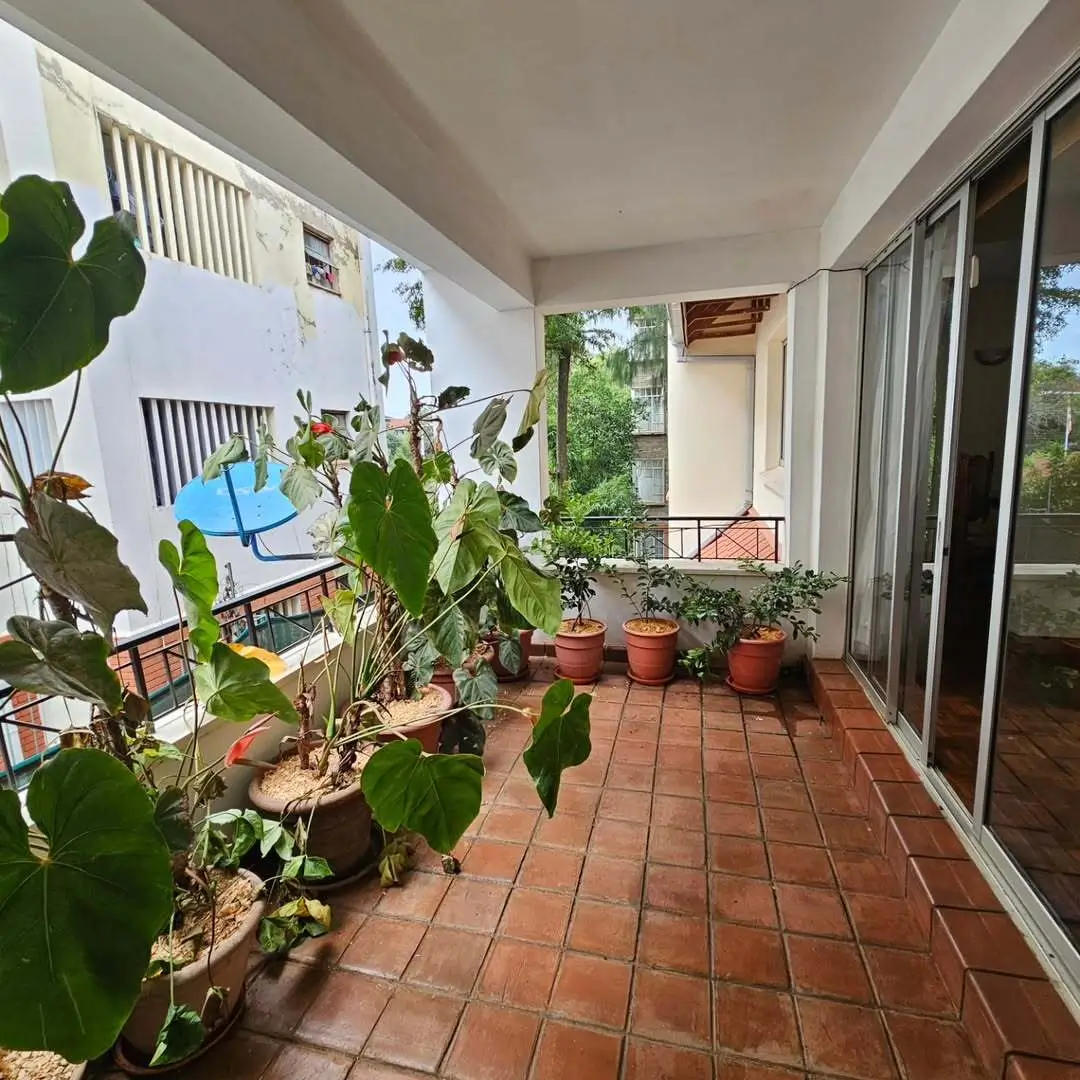 Spacious terracotta-tiled balcony with potted plants and garden views