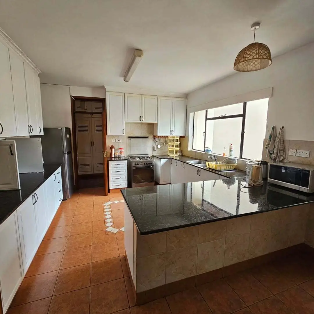 Spacious kitchen with white cabinetry, dark countertops, island