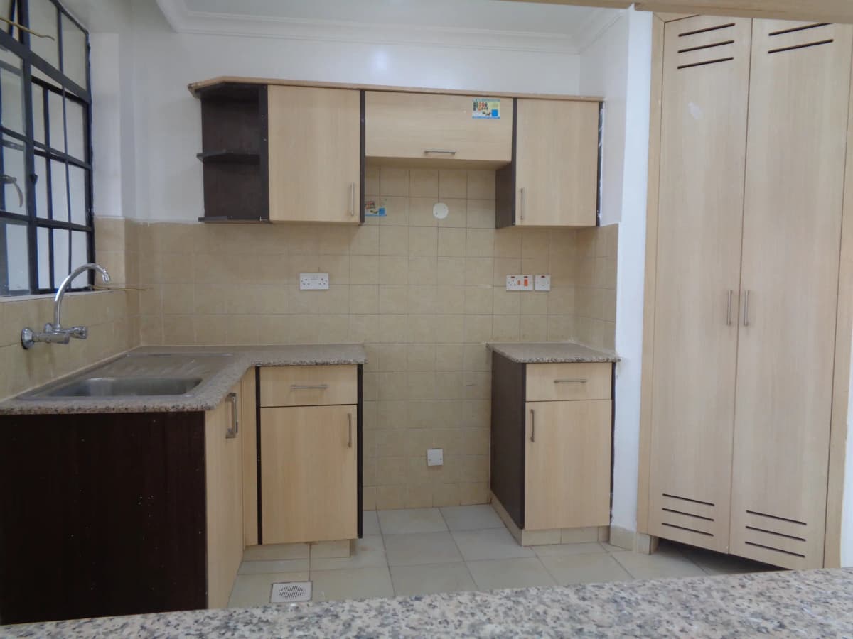 Compact kitchen with cream cabinetry and dark countertops