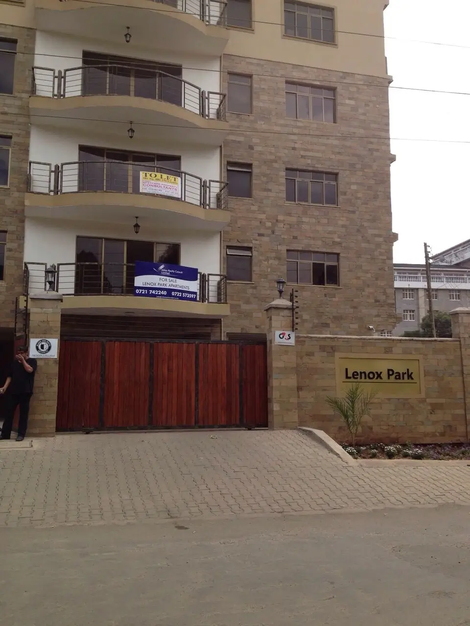 Modern brick apartment building with balconies and red gate entrance