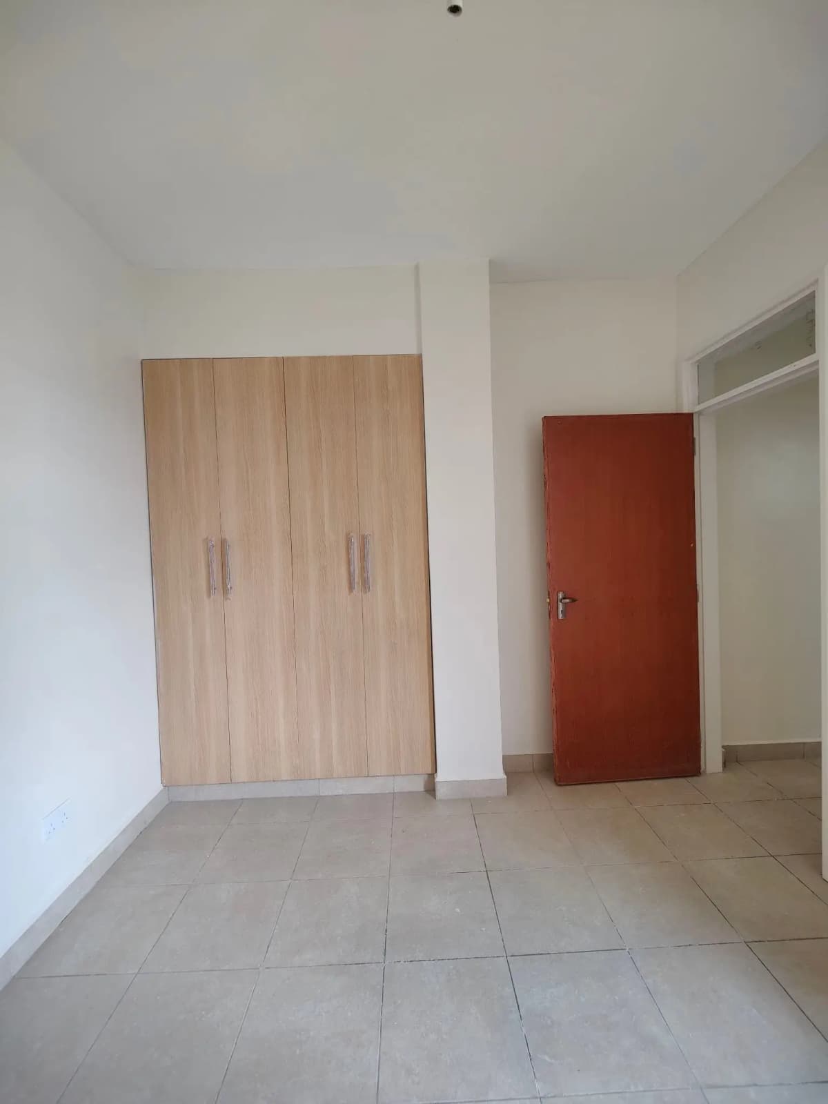 Unfurnished bedroom with built-in wardrobes and tiled floor