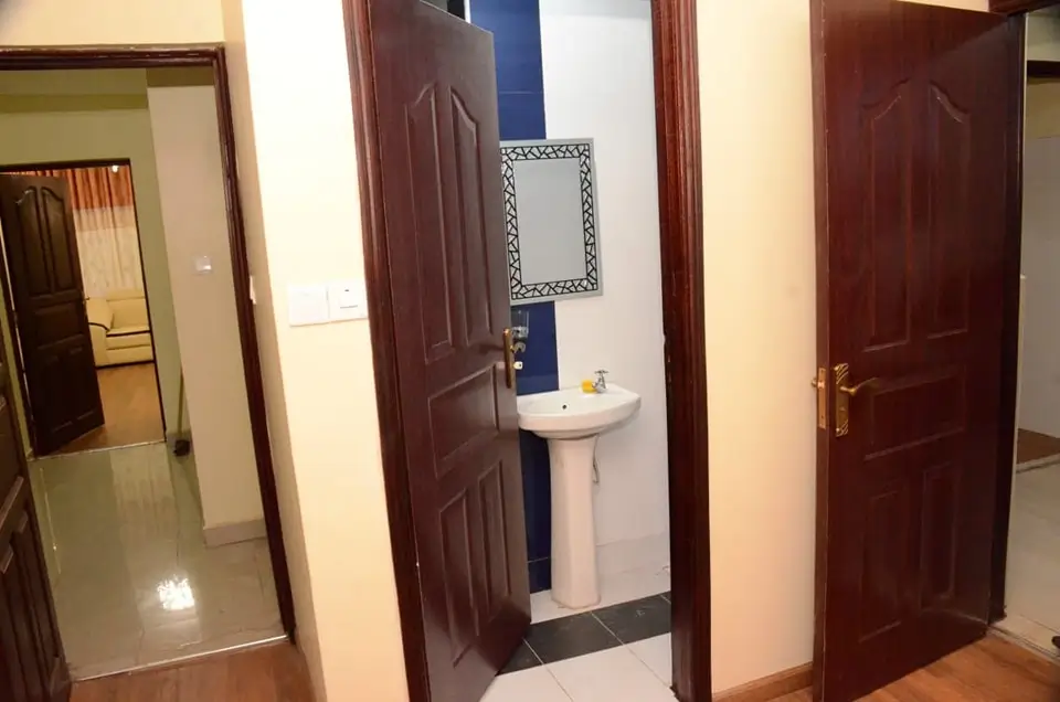 Compact bathroom with pedestal sink and decorative mirror