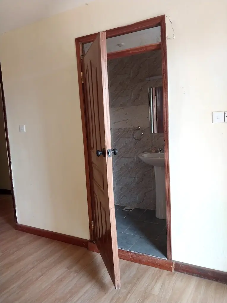En-suite bathroom with dark tile flooring and glass door entry