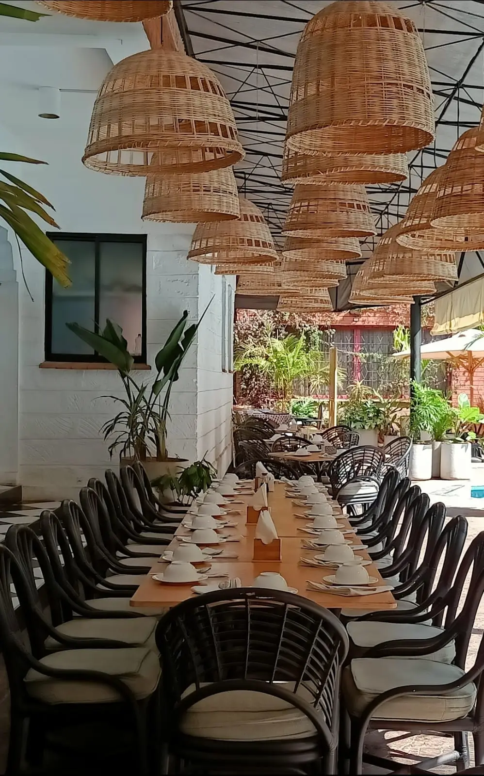 Long dining table with black chairs and woven pendant lights
