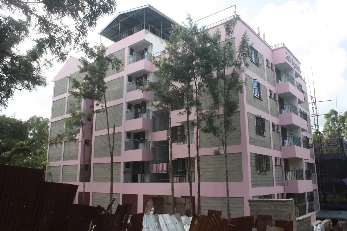 Pink multi-story residential building with balconies and landscaping