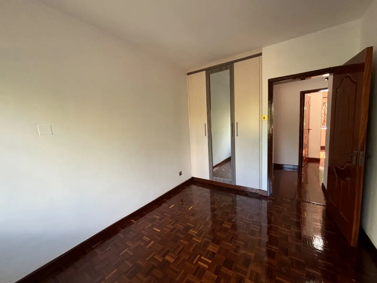 Spacious bedroom with built-in wardrobe and polished wood floor