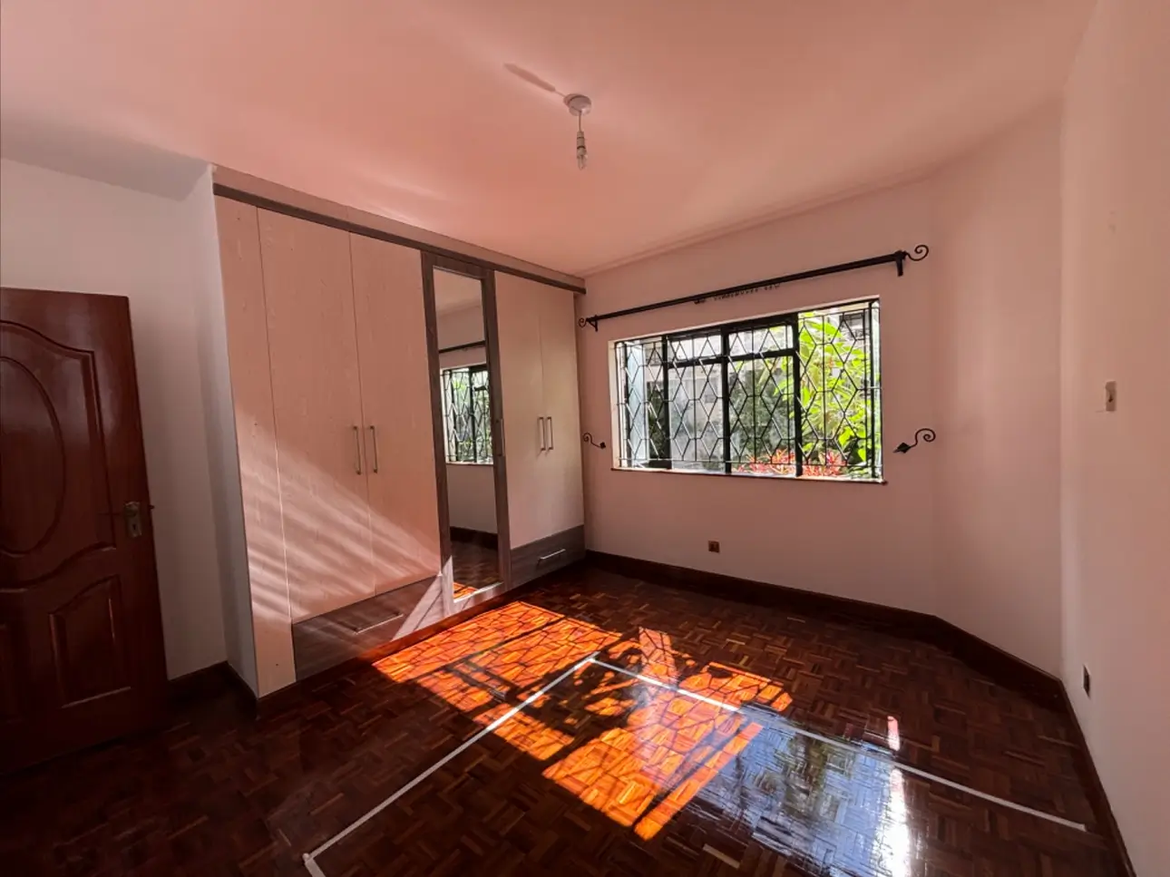 Spacious bedroom with dark wood floors and large windows