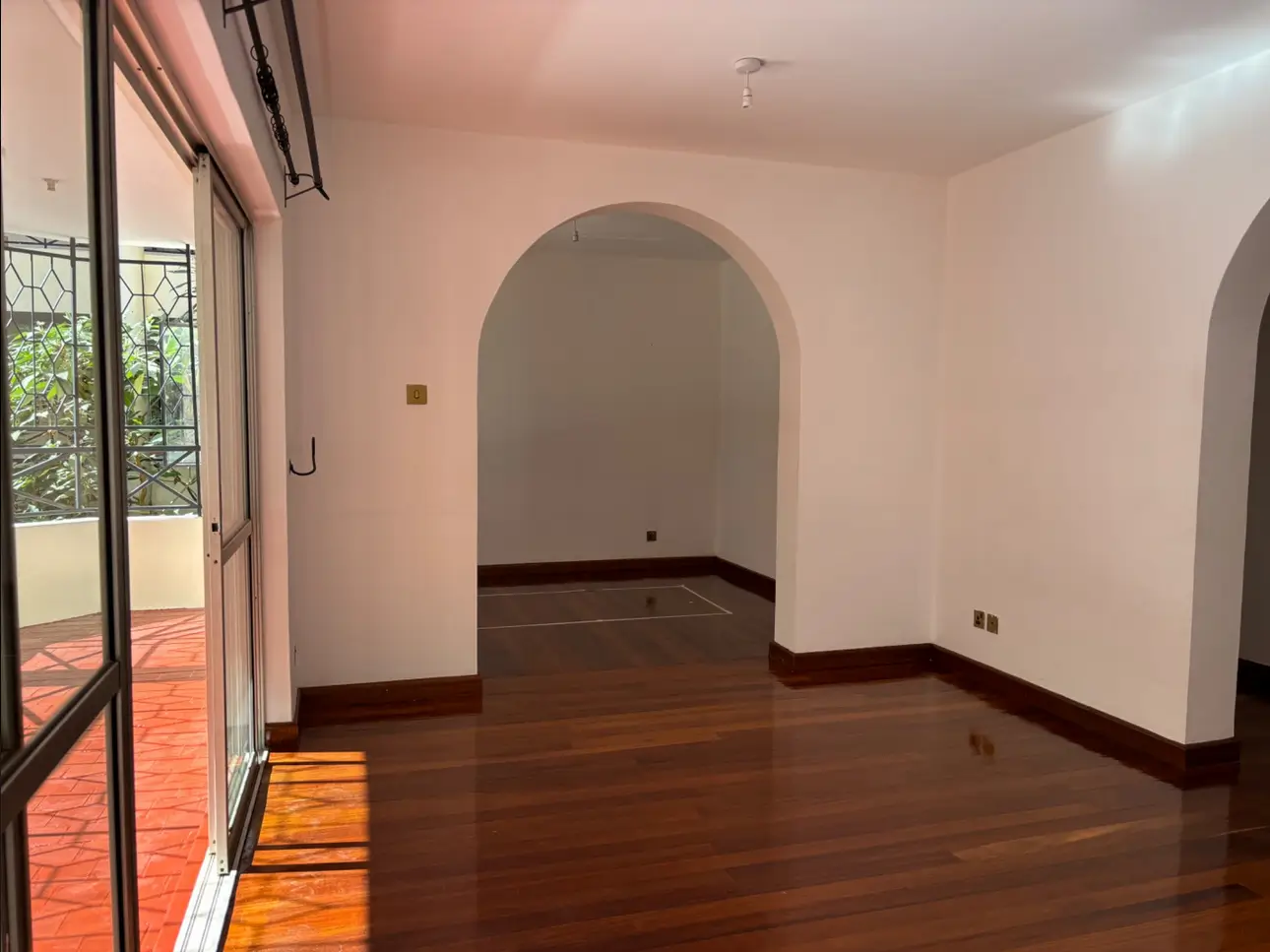 Spacious living room with arched doorway and wooden flooring