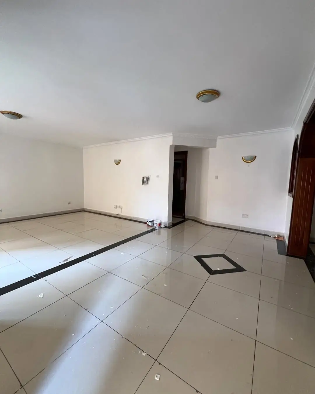 Empty living room with white tile flooring and recessed lighting