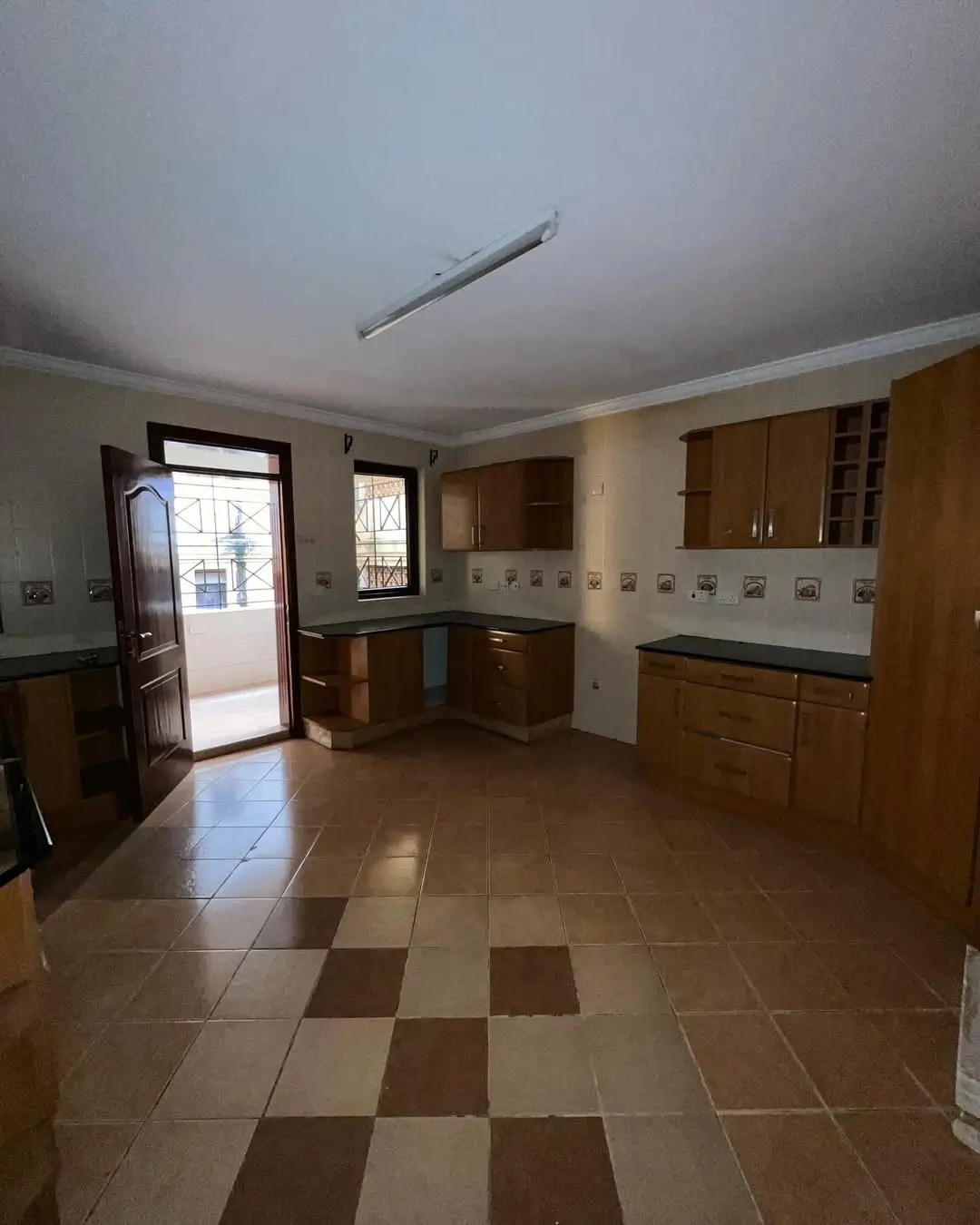 Open-plan kitchen with wooden cabinets and checkerboard tile flooring
