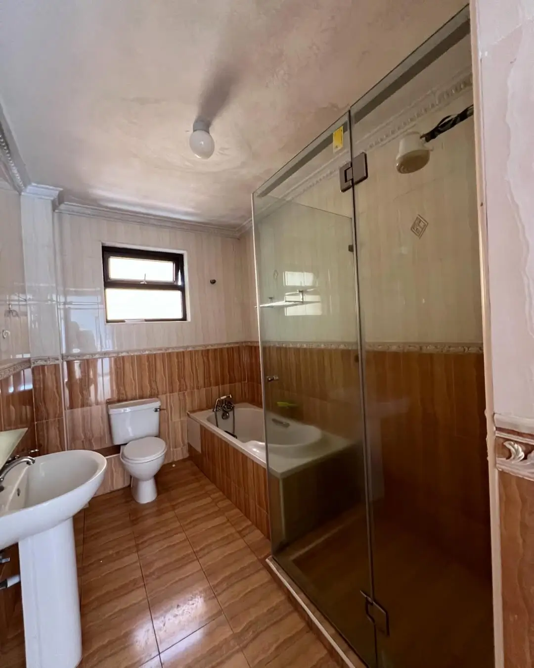 Spacious bathroom with wooden paneling and walk-in shower