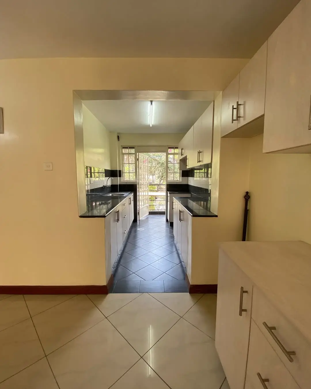 Galley kitchen with black countertops and cream cabinetry