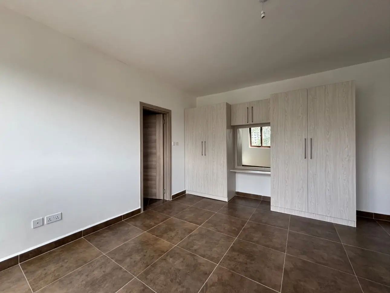 Spacious bedroom with built-in wardrobes and dark tile flooring
