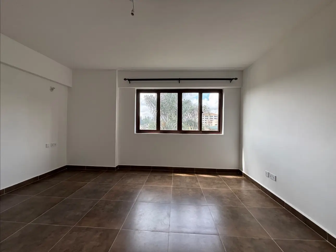 Spacious empty living room with dark tile flooring and natural light