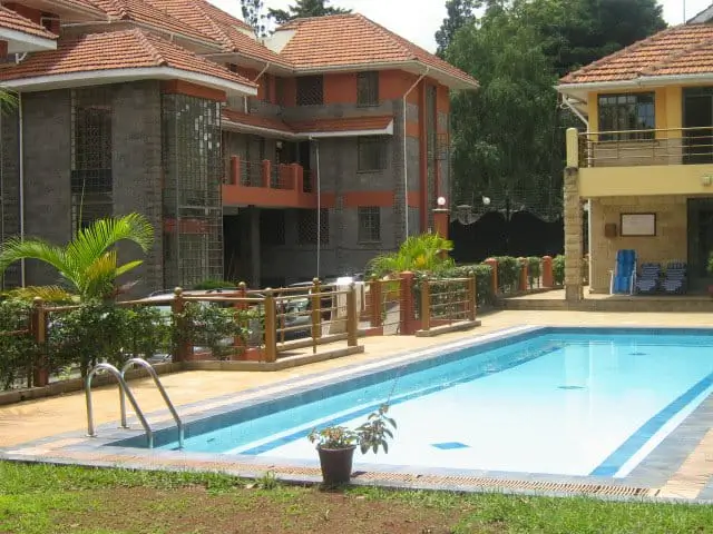 Residential swimming pool with surrounding manicured grounds and palm trees