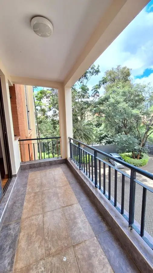 Spacious balcony with railing overlooking lush green trees