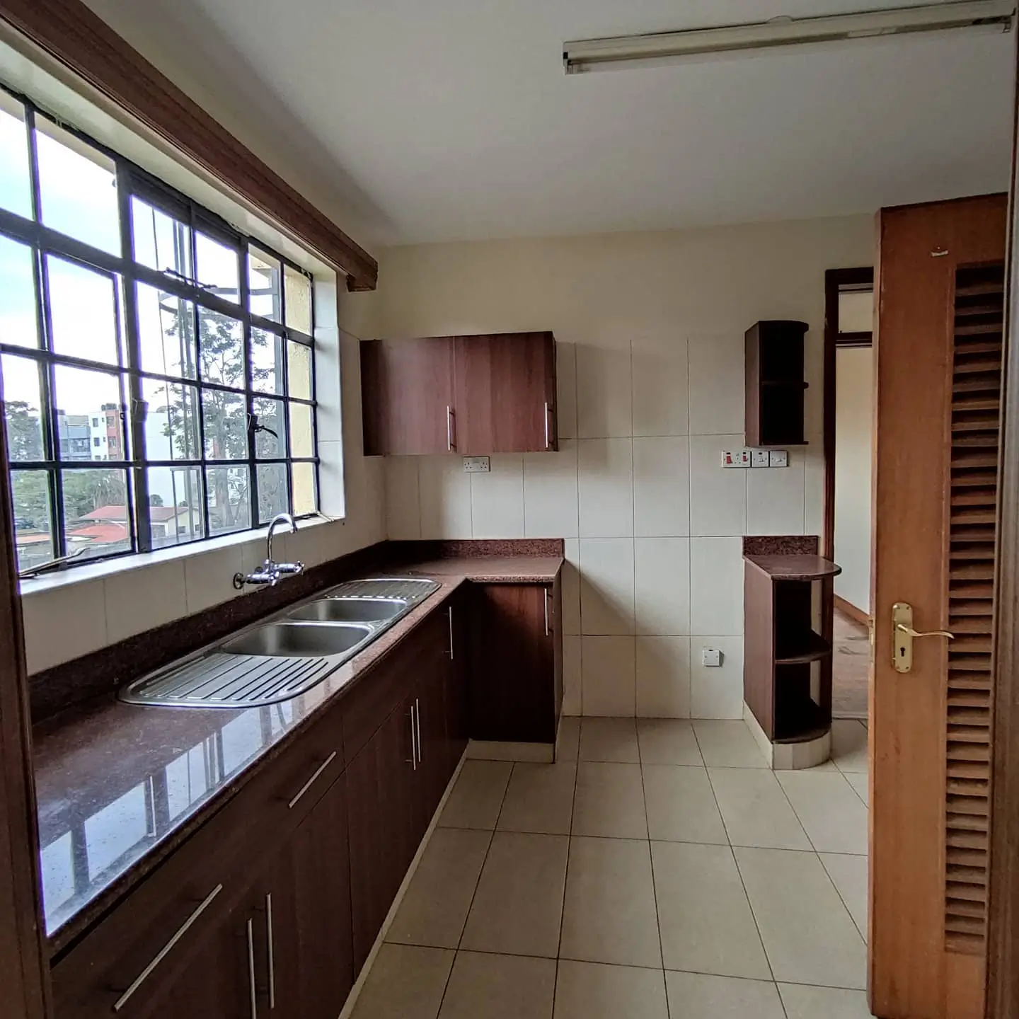 Kitchen with dark cabinetry, stainless sink, and large window