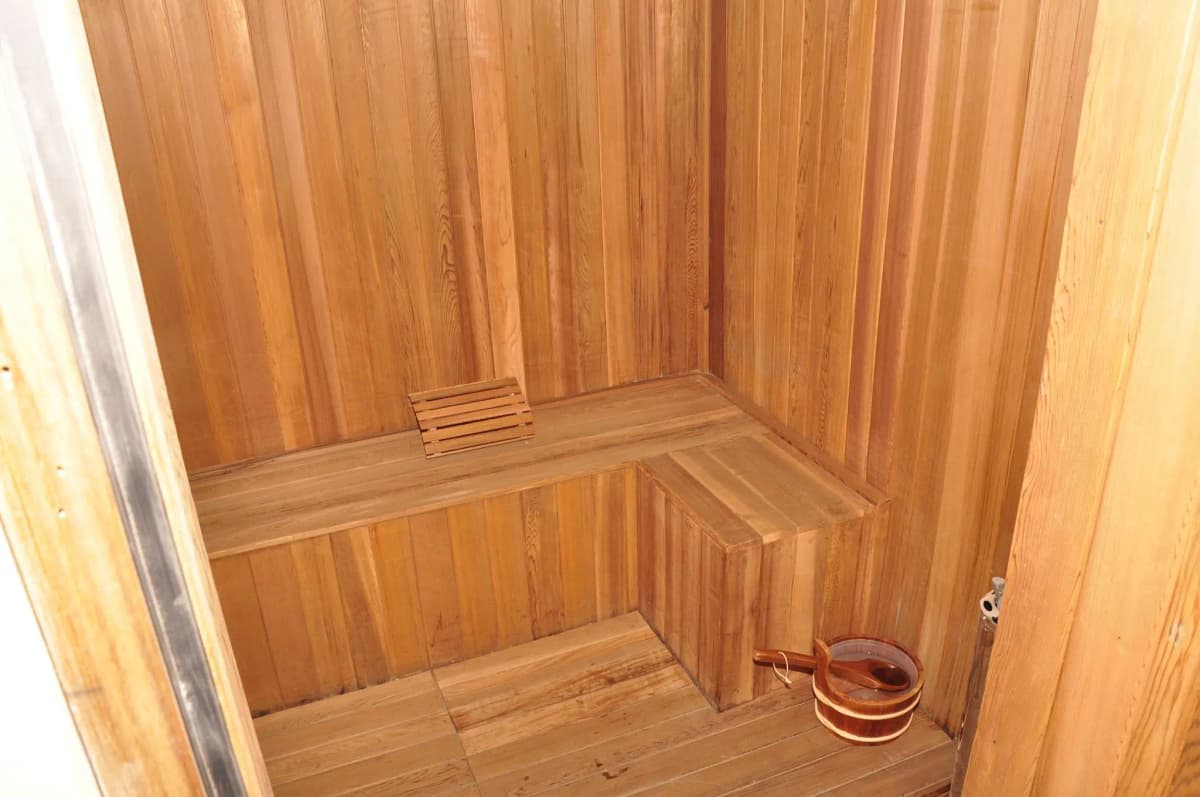 Wooden sauna interior with tiered benches and bucket