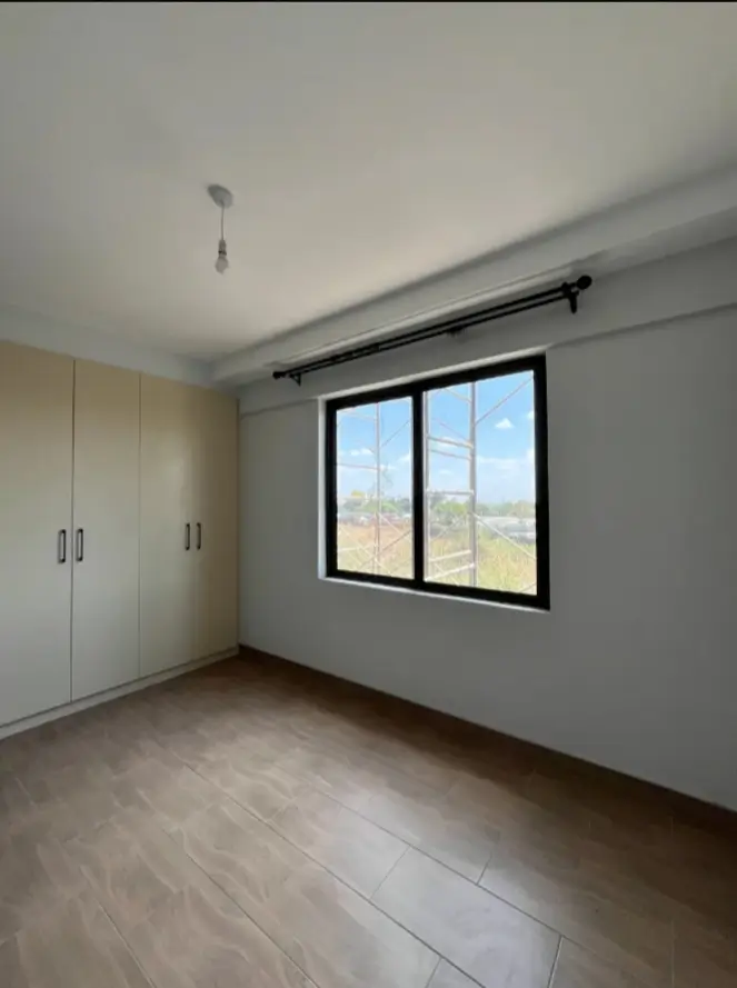 Empty bedroom with built-in wardrobes and wood-look flooring