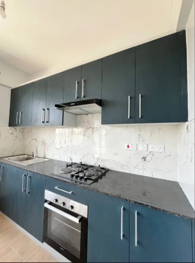 Sleek teal cabinets with dark granite countertop and built-in oven