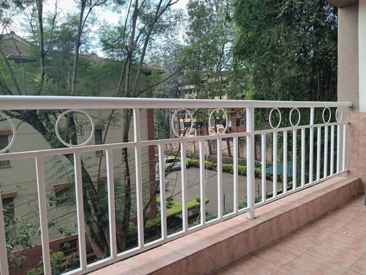 Balcony with white metal railing overlooking green compound