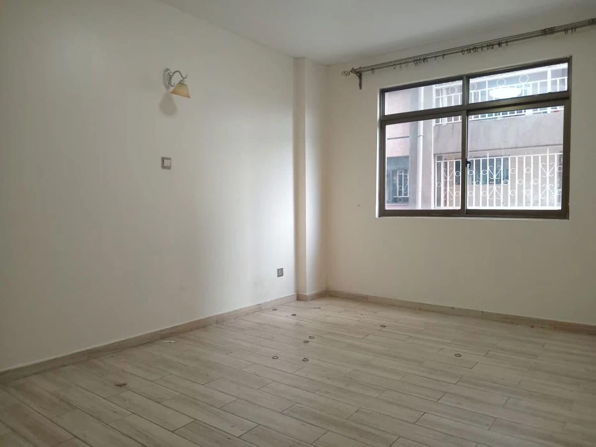 Spacious empty living room with large windows and light wood flooring