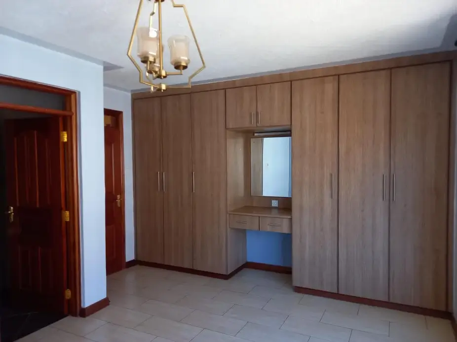 Spacious bedroom with built-in wooden wardrobes and study nook