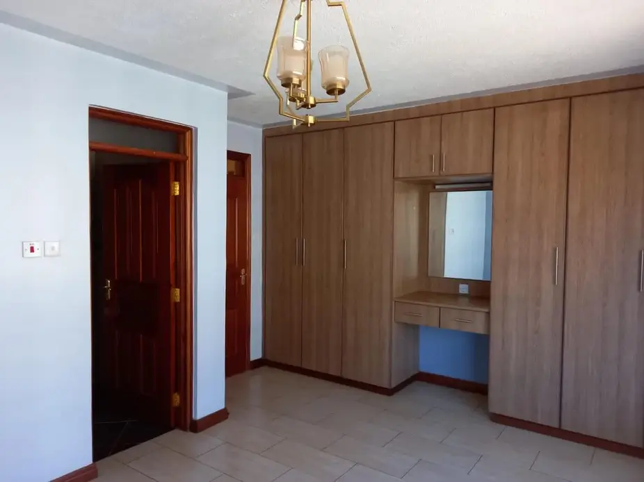 Spacious bedroom with built-in wooden wardrobes and pendant light