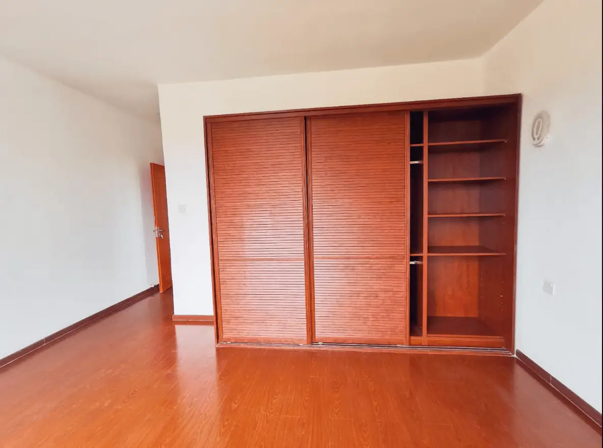 Empty bedroom with wooden wardrobe and built-in shelving