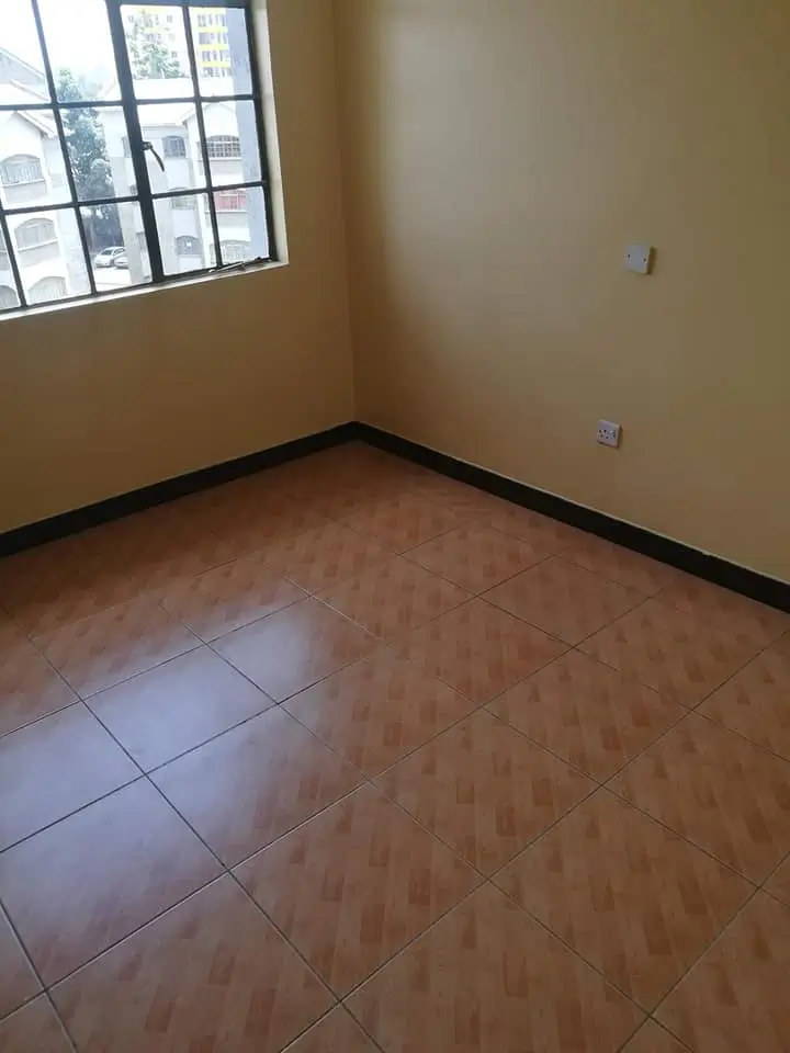 Empty bedroom with wooden flooring and natural light