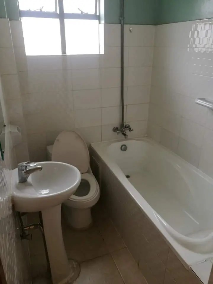 Compact bathroom with toilet, pedestal sink, and bathtub