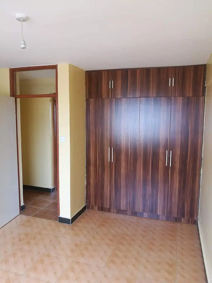 Spacious bedroom with built-in wooden wardrobe and entrance