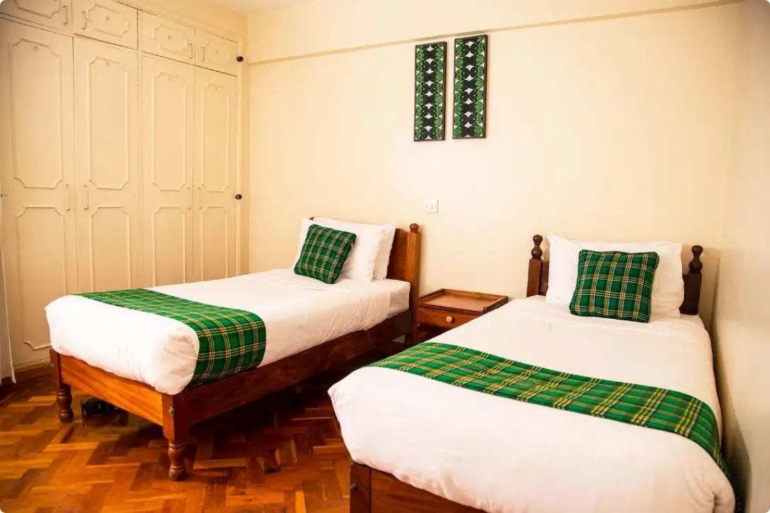 Twin bedroom with wooden beds, green tartan accents, parquet flooring