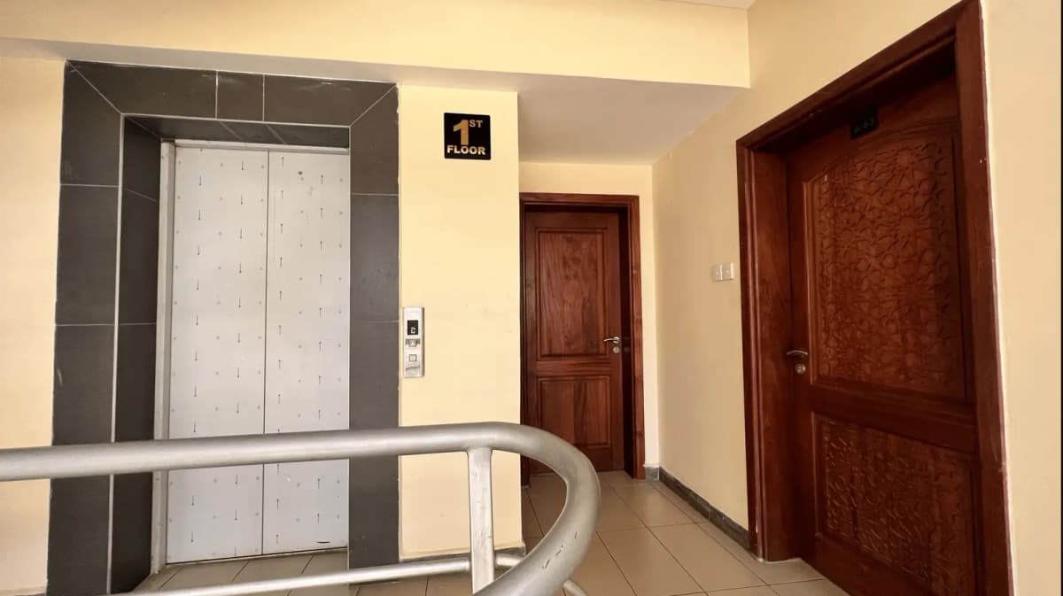Building lobby with elevator, wooden doors, handrail