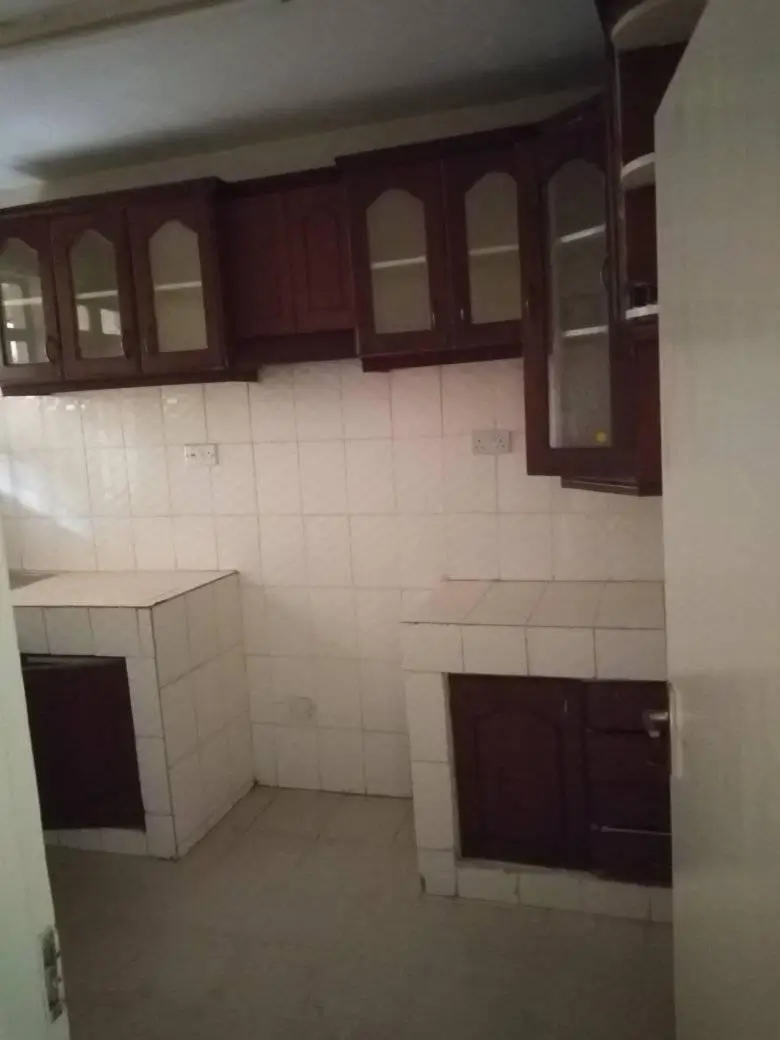 Unfurnished kitchen with white tile walls and dark cabinetry