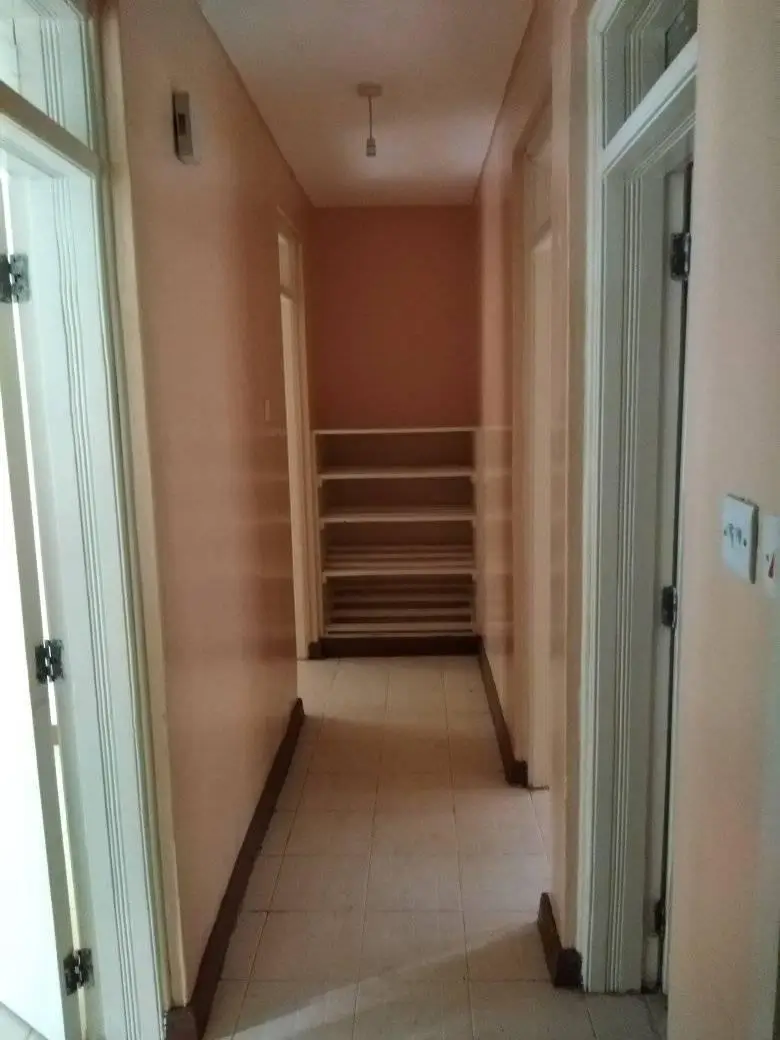 Narrow hallway with wooden shelving and white doors