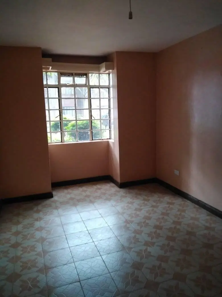 Spacious bedroom with large barred window and terracotta walls
