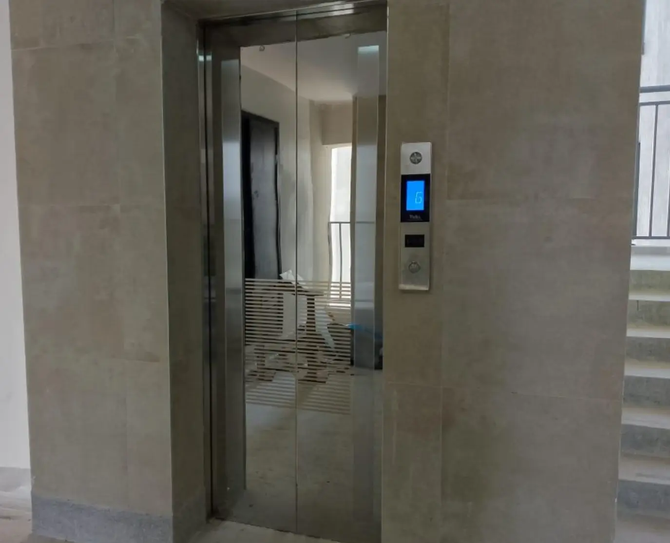Modern elevator with digital display in neutral-toned lobby