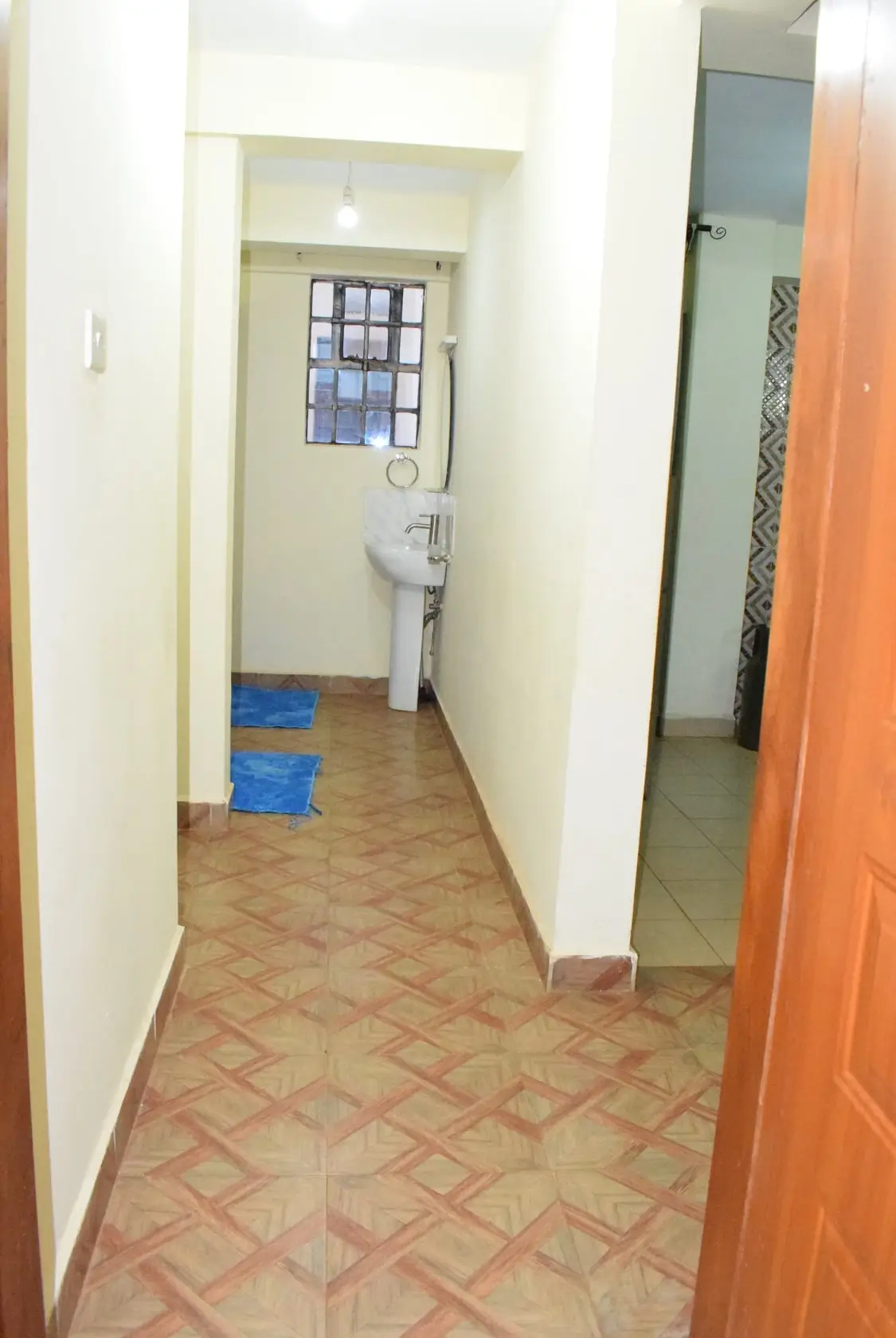 Narrow hallway with terracotta tile flooring and white walls